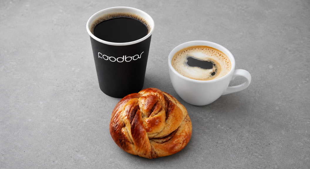 Kaffe, cappuccino og kanelbolle på grå bakgrunn