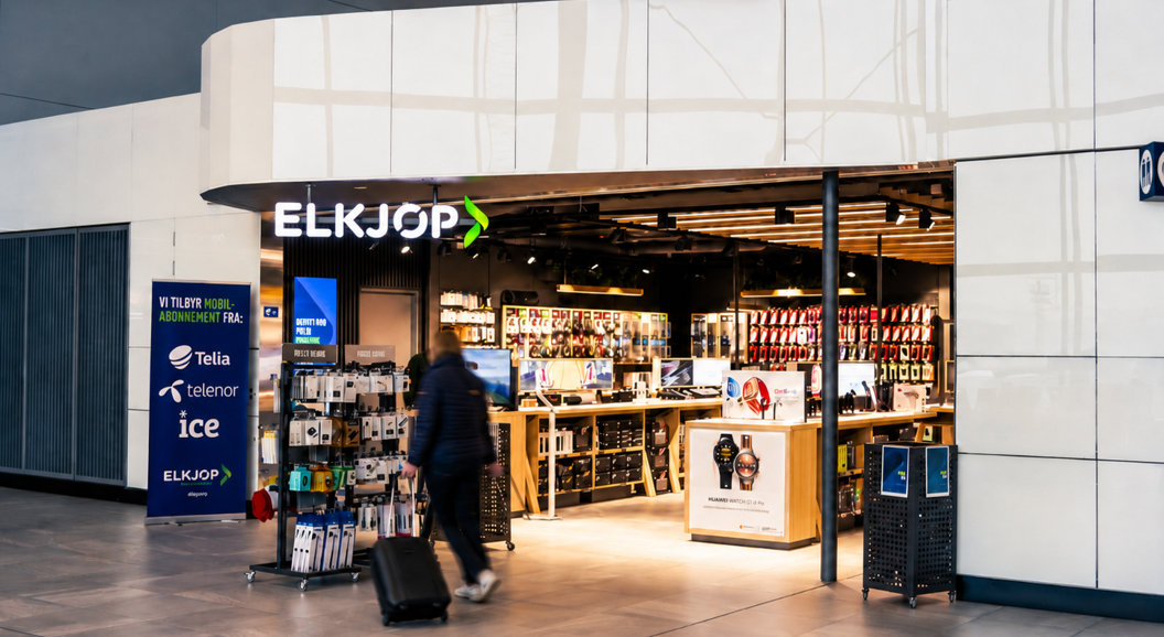 Butikkmedarbeider hjelper en kunde med hodetelefoner i en moderne elektronikkbutikk, omgitt av telefontilbehør