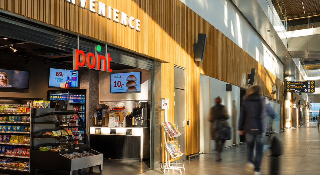 Kvinne som ser på magasiner ved en aviskiosk, med ulike fargerike magasinomslag og publiseringer