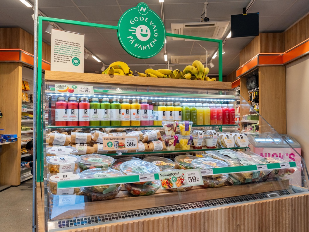 Moderne Narvesen-kiosk på en flyplass som tilbyr nødvendighetsartikler, snacks og drikkevarer under levende belysning