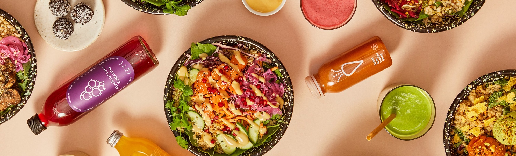 Fargerike salatskåler, wraps og smoothieflasker med ulike ingrediensar som grønsaker, frø og sausar, sett ovanfrå på ein lysebrun bakgrunn
