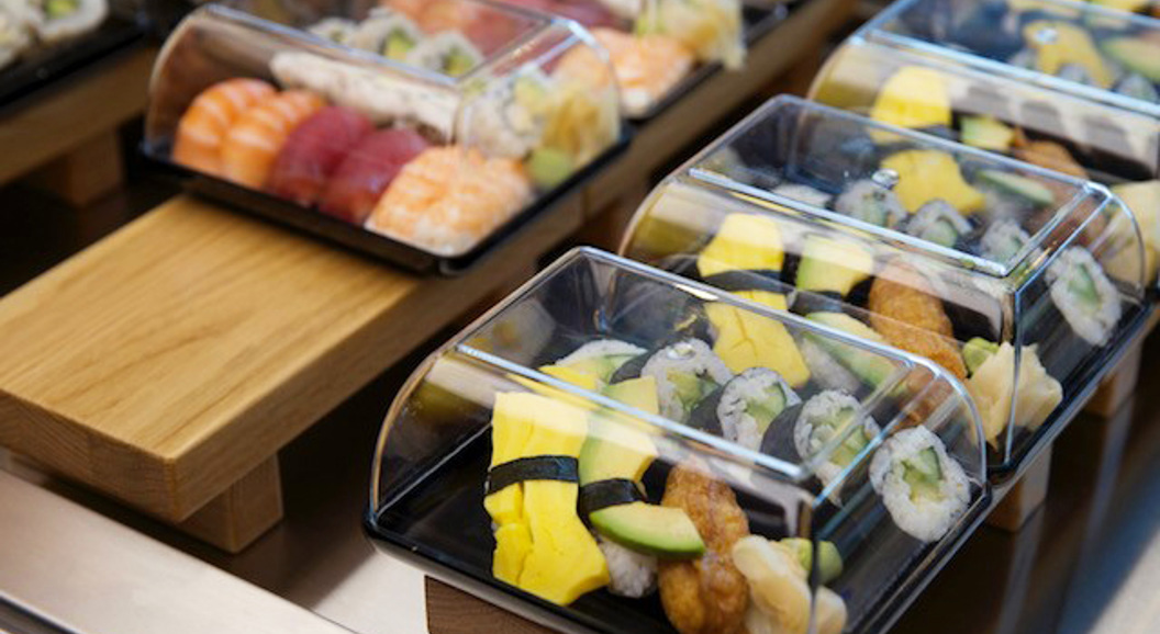 Sushi i plastboksar på utstillingsbord, med variasjonar av nigiri og maki med fersk laks, tunfisk og egg