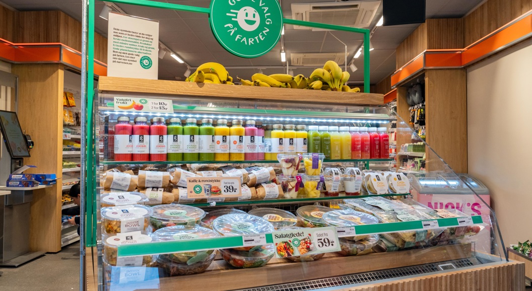 Moderne Narvesen-kiosk på en flyplass som tilbyr nødvendighetsartikler, snacks og drikkevarer under levende belysning