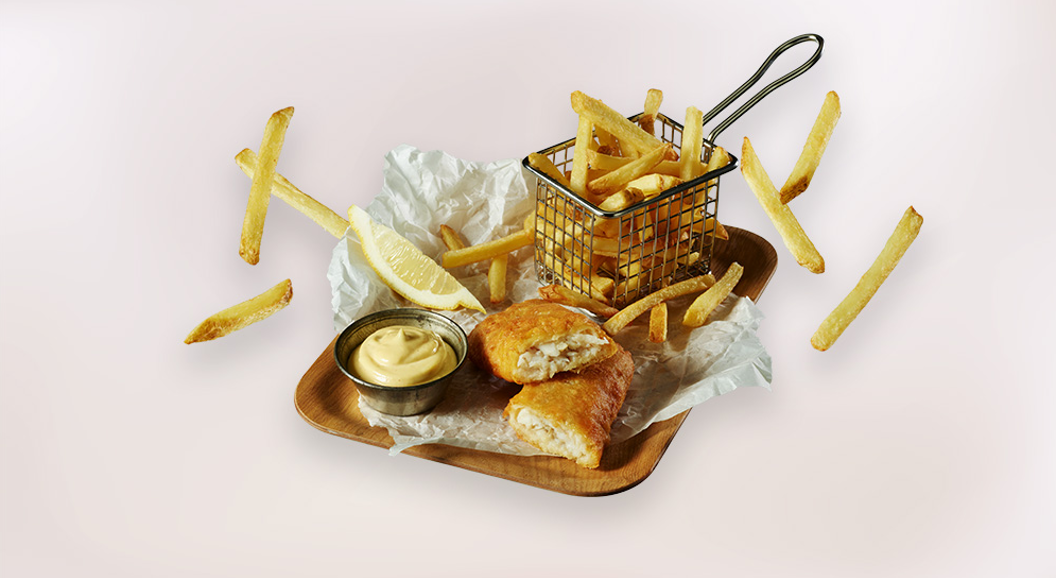 Fish and chips med sprø pommes frites, sitron og remulade på serveringsbrett
