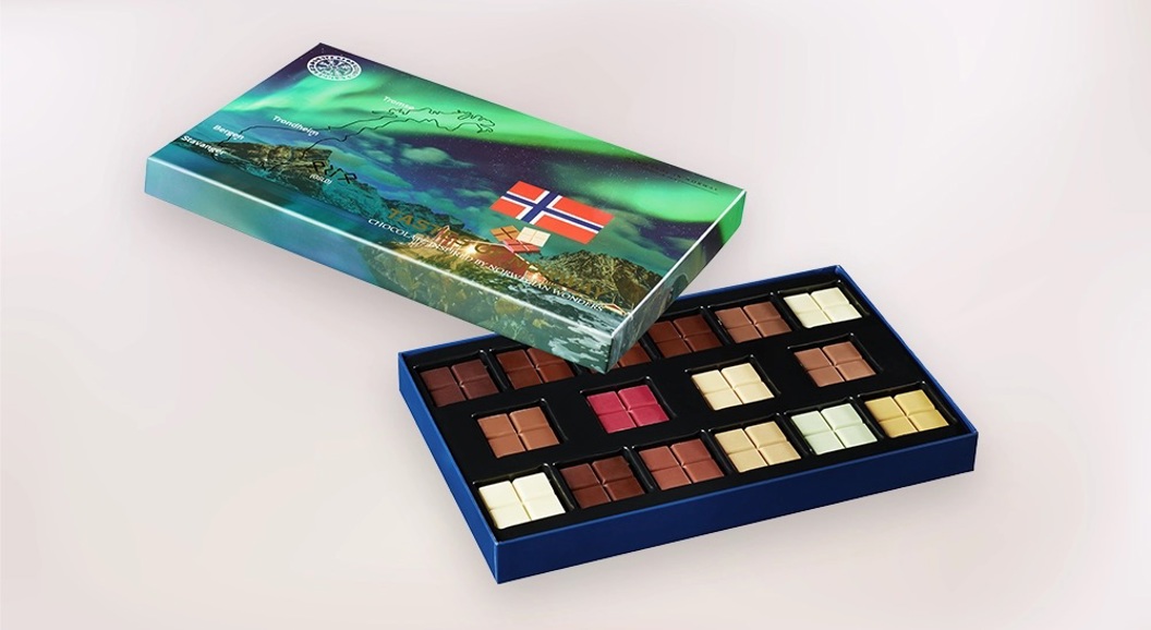 Åpen gaveeske med sjokoladebiter i norsk design og flaggmotiv på lokket