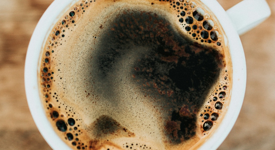 Oversikt over en rykende svart kaffe i en hvit kopp på et rustikt trebord