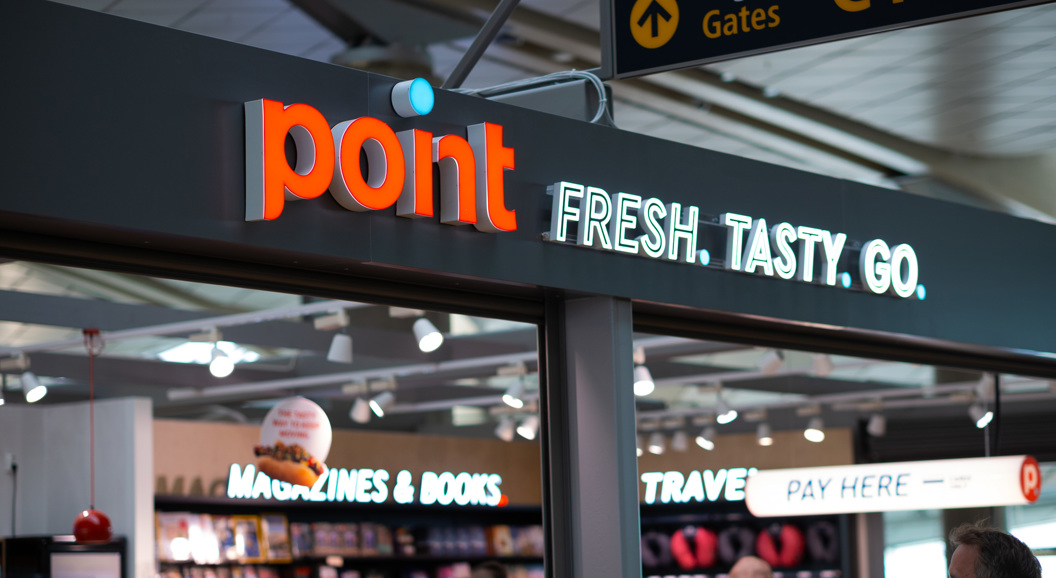 Butikkskilt med teksten "point" og slagordet "FRESH. TASTY. GO." i ein flyplassbutikk