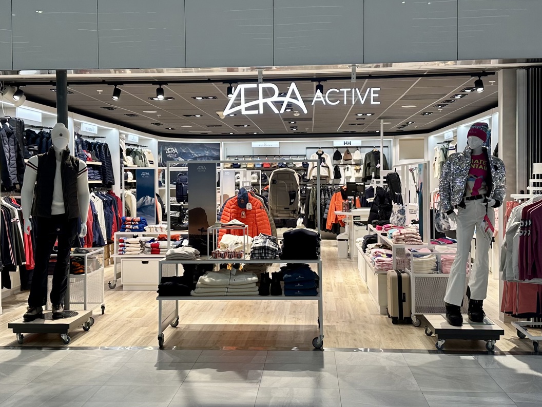 Exterior view of Aera Active clothing store, showcasing mannequins dressed in outdoor apparel and vibrant winter clothing, with well-organized shelves and racks displaying various fashion items inside the modern retail space