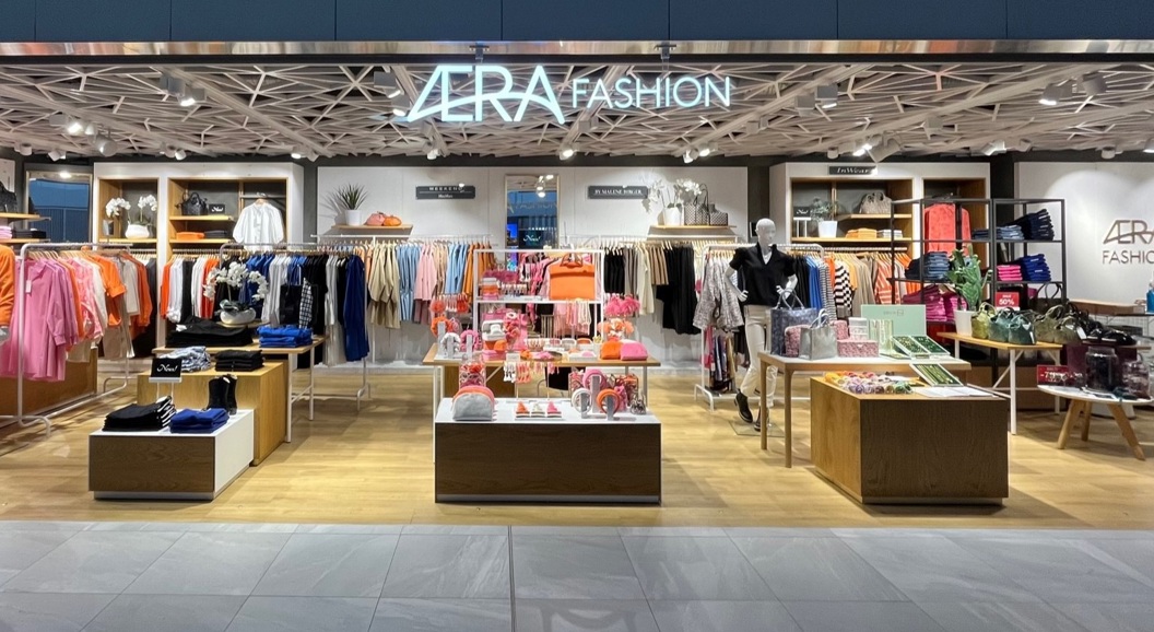 Modern fashion store interior with a variety of colorful clothing and accessories on display, featuring stylish mannequins and organized racks under soft lighting