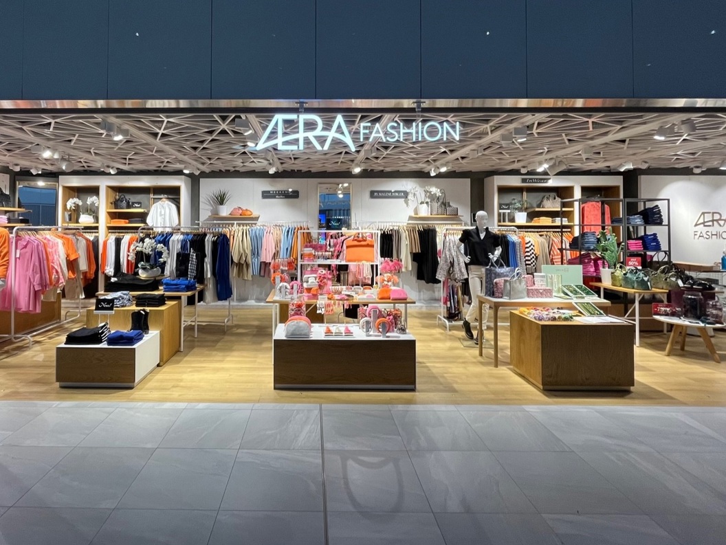 Modern fashion store interior with a variety of colorful clothing and accessories on display, featuring stylish mannequins and organized racks under soft lighting