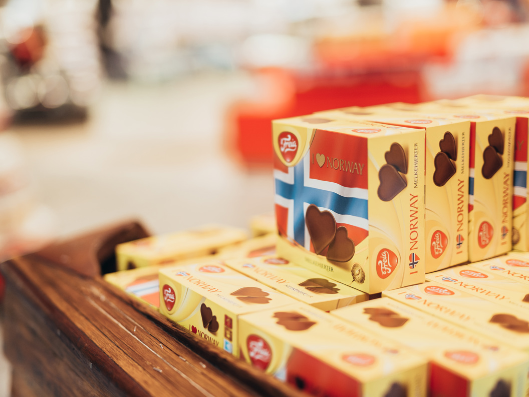 Norwegian chocolate boxes with flags displayed on a wooden shelf in a store