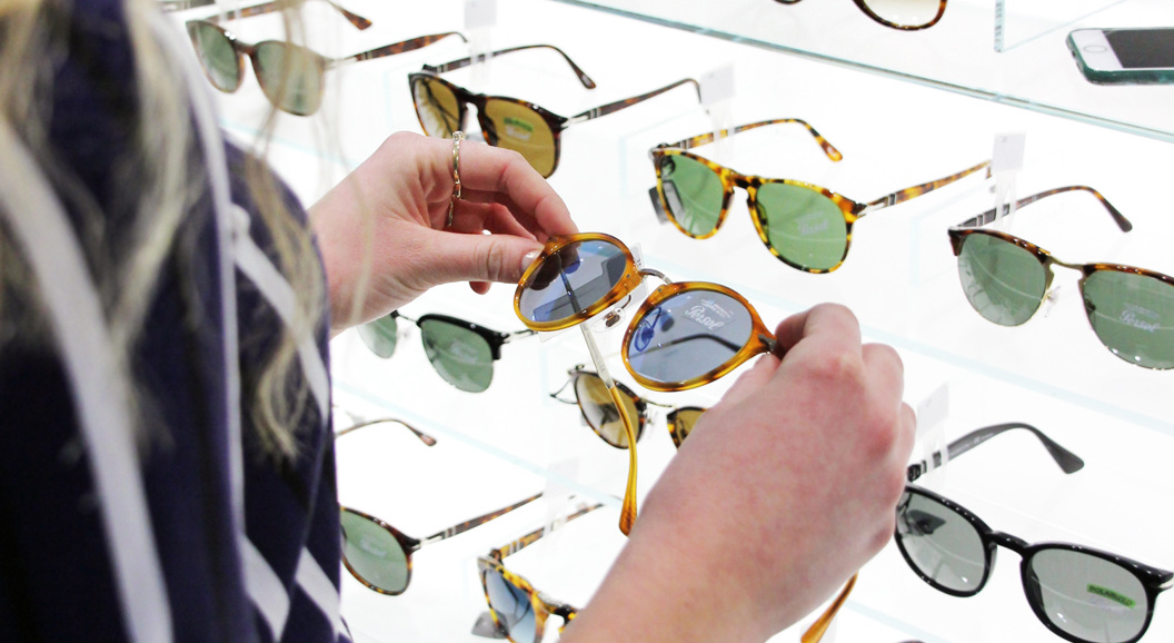 Woman examining designer sunglasses at an eyewear store display