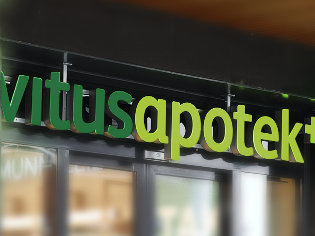 Vitusapotek skilt på bygning, grøne og kvite bokstavar i moderne design