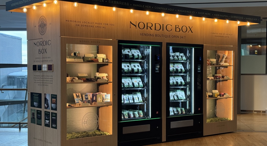 Nordic Box vending boutique in airport, offering locally crafted gifts. Features illuminated display shelves and vending machines stocked with assorted items. Open 24/7