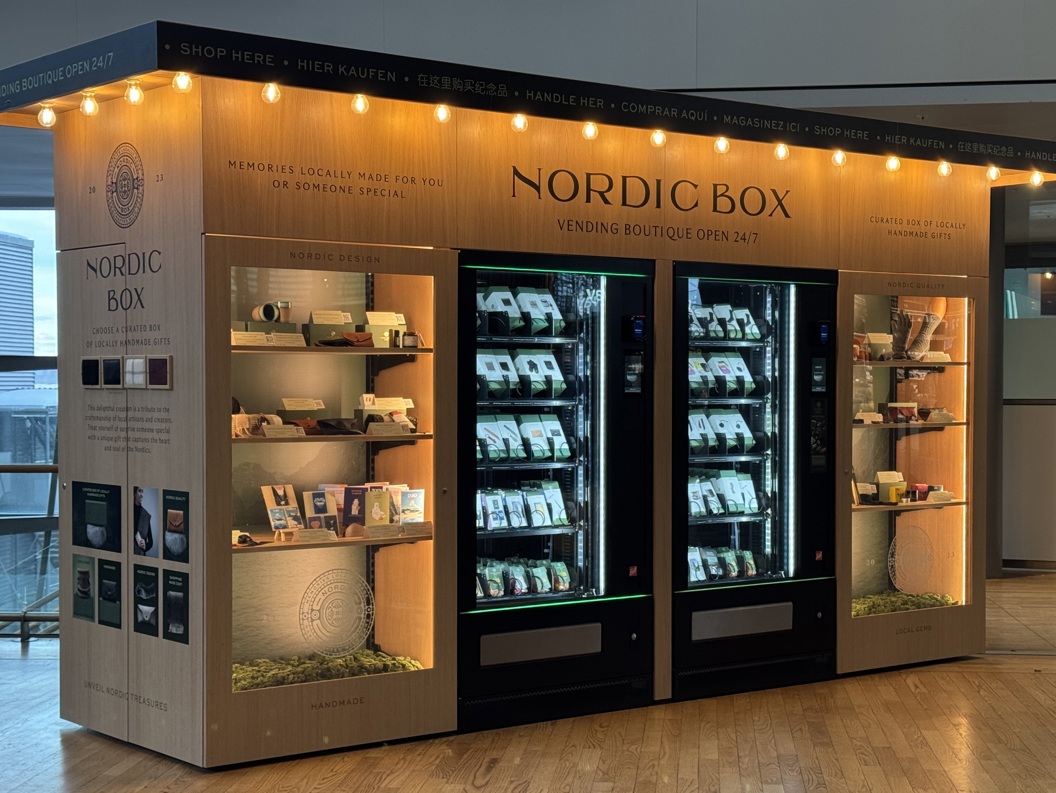 Nordic Box vending boutique in airport, offering locally crafted gifts. Features illuminated display shelves and vending machines stocked with assorted items. Open 24/7