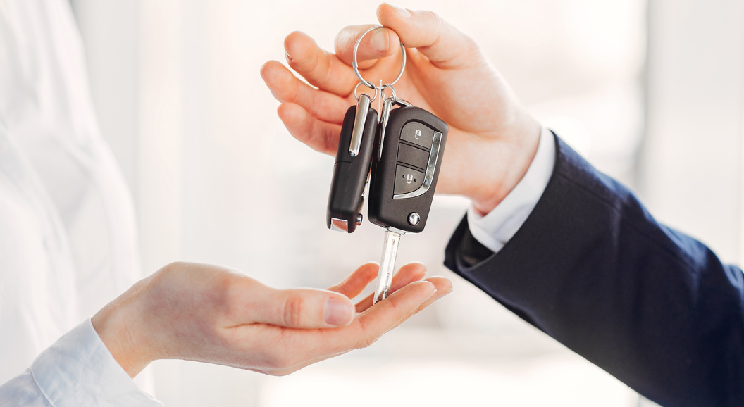 Person handing over car keys to another, symbolizing car rental or vehicle purchase exchange