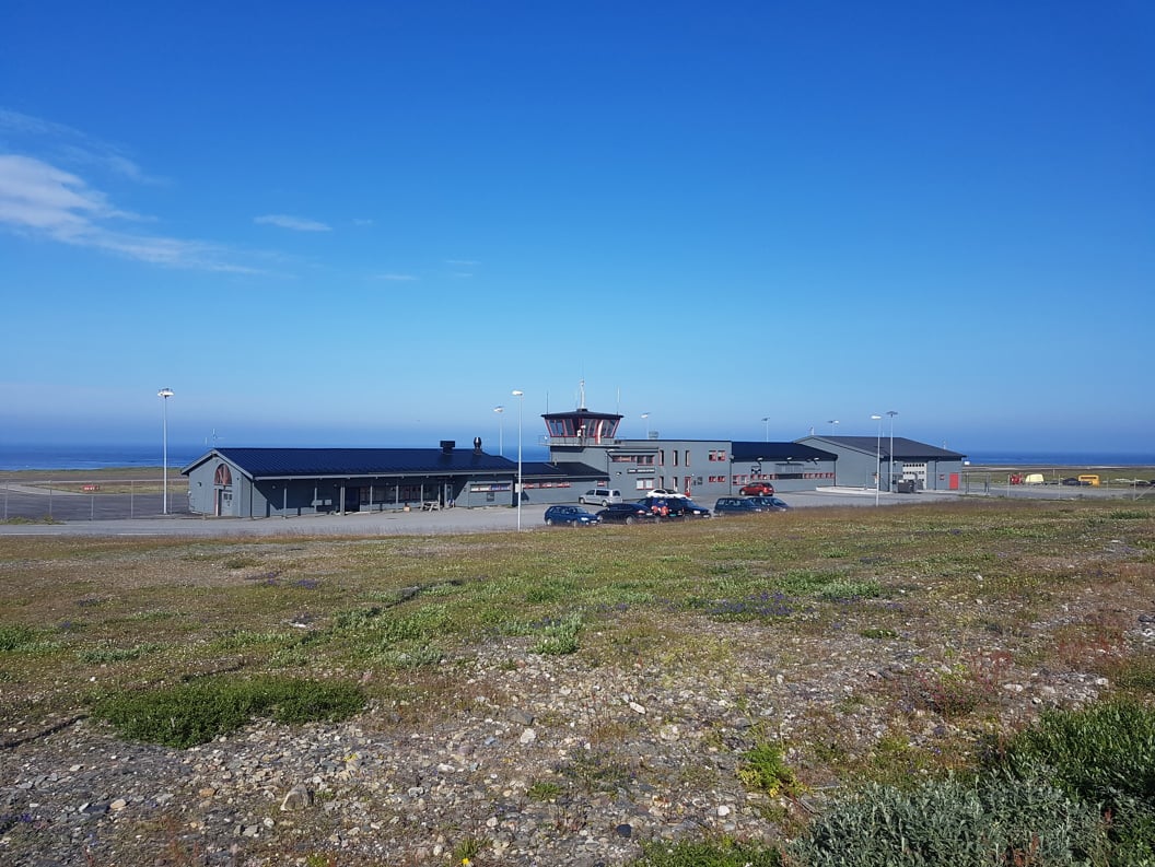 Berlevåg flyplass med kontrolltårn på øde landskap, blå himmel i bakgrunnen.