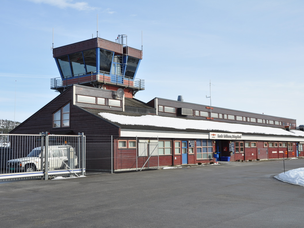 Kontrolltårn ved Førde flyplass i snølandskap, med blå himmel i bakgrunnen.