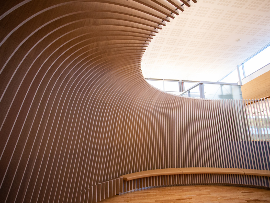 Moderne interiørdesign med buet trepaneler og naturlig lys i et rom for stillhet.