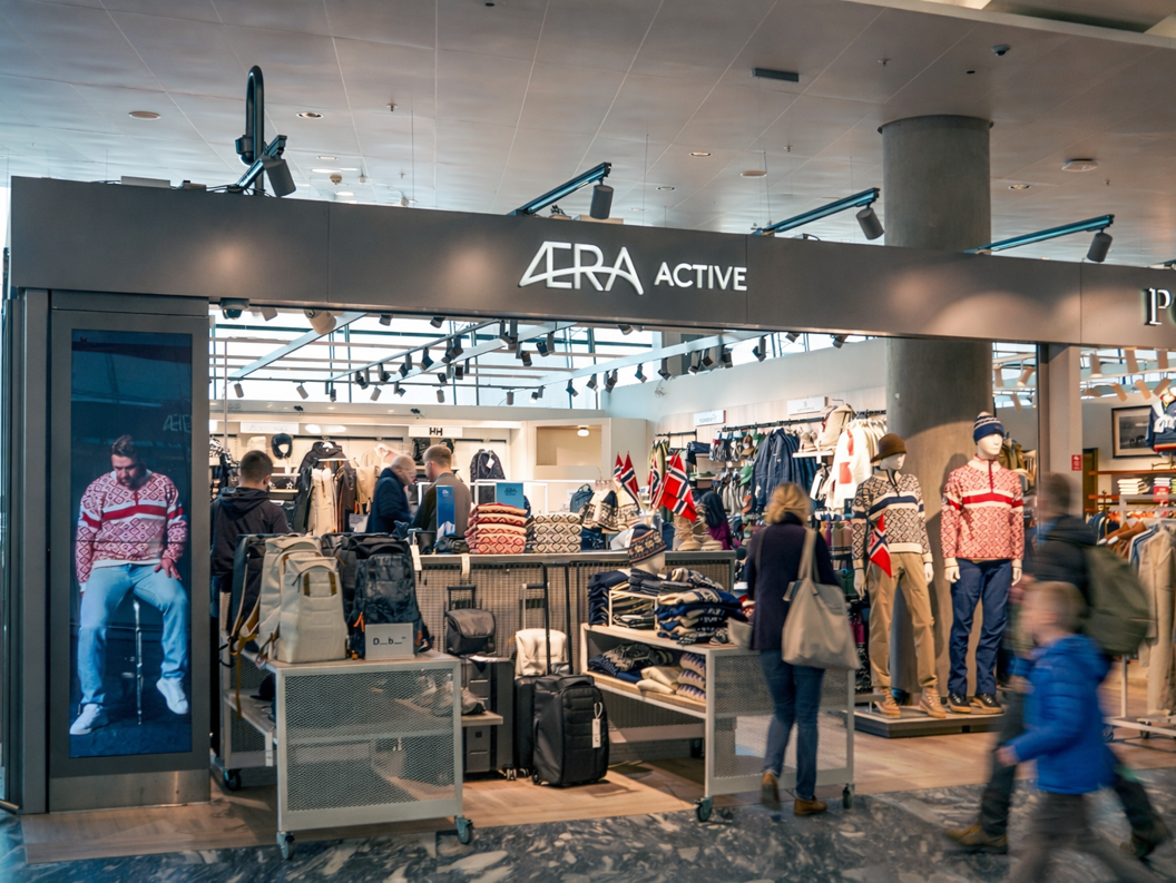 Men's clothing store interior with neatly stacked shirts, jackets on a rack, and a mannequin wearing a beige blazer, showcasing a stylish, organized retail display