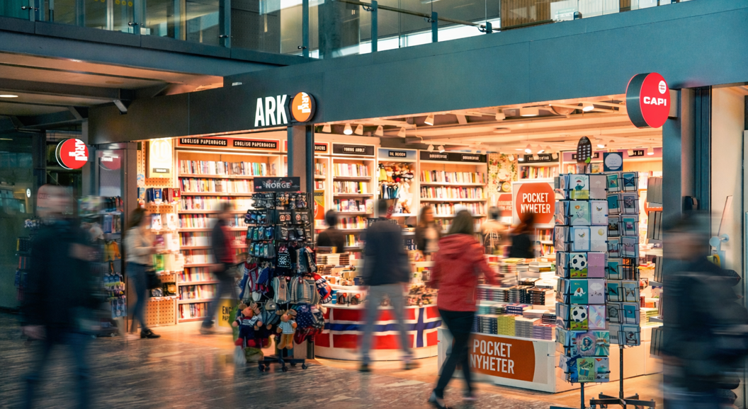 A woman browsing colorful children's books on a green bookshelf in a bookstore, focused on selecting a title