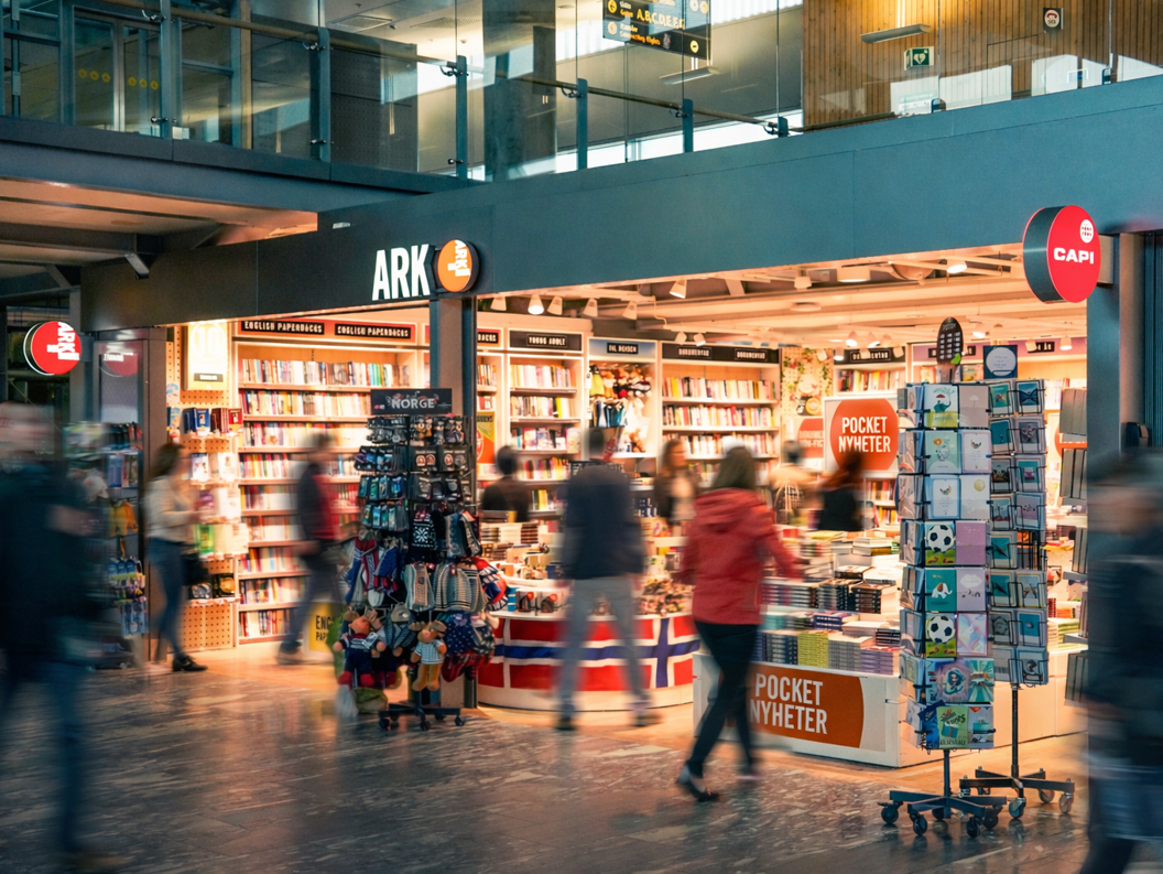A woman browsing colorful children's books on a green bookshelf in a bookstore, focused on selecting a title