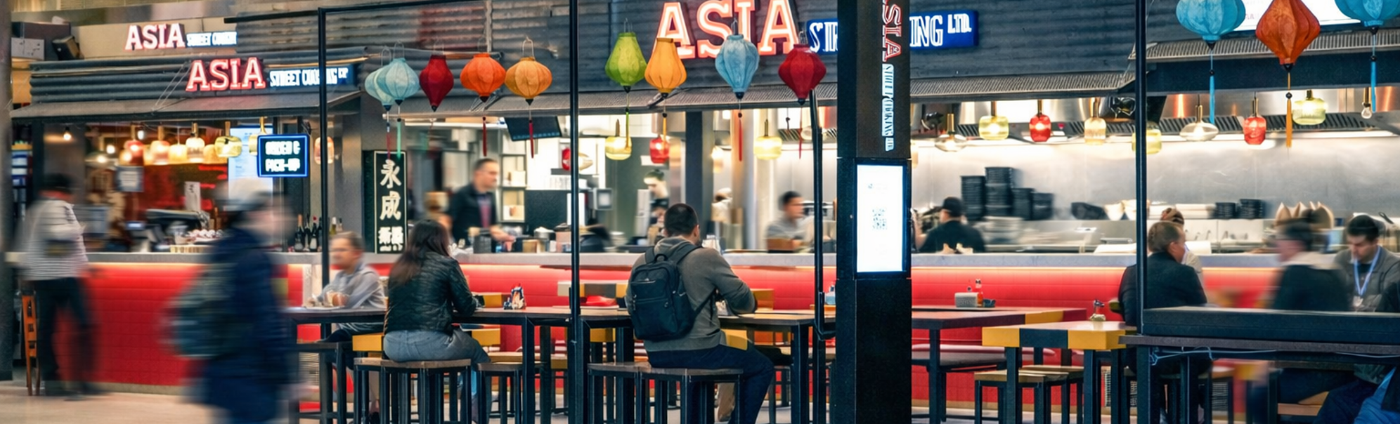 Gatekjøkken med asiatisk mat i fargerik innredning, med skilt for bestilling og henting. Moderne design med røde fliser og trebenker