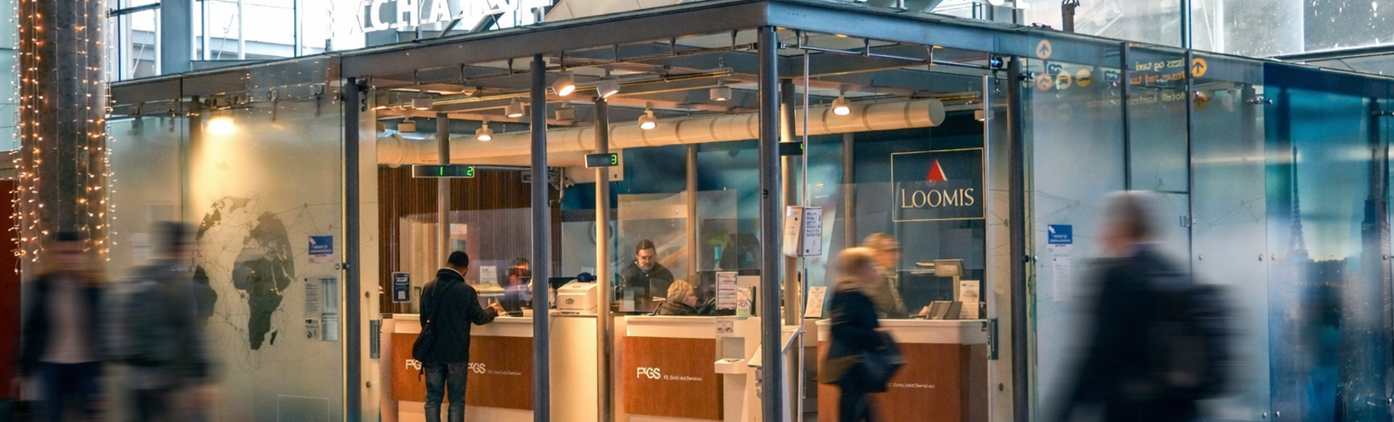 En person som bruker en minibank for utenlandsk valuta på en flyplass, med flere valutamuligheter vist på en skjerm i nærheten, som indikerer internasjonal reise og finansielle transaksjoner