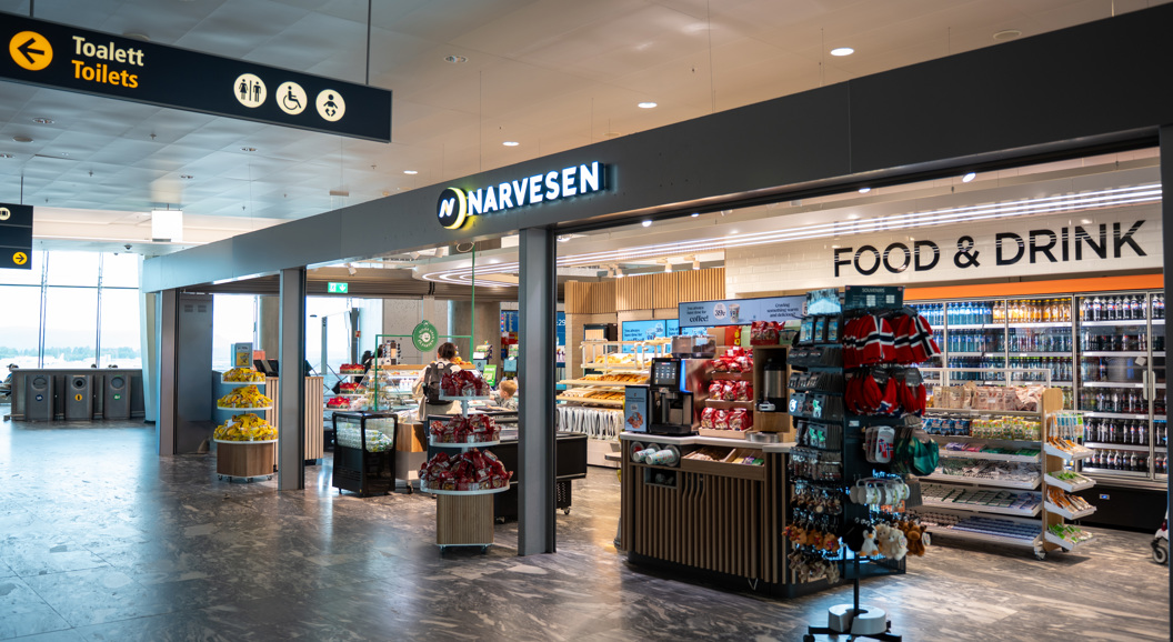 Moderne Narvesen-kiosk på en flyplass som tilbyr nødvendighetsartikler, snacks og drikkevarer under levende belysning