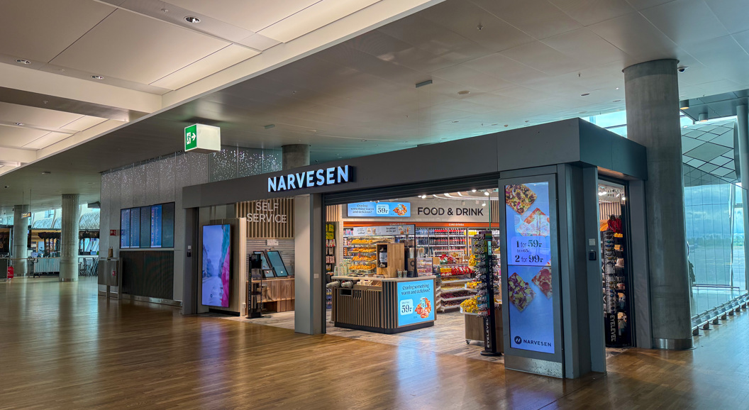 Narvesen-kiosk med food & drink i en moderne flyplassterminal med tomt gulv og selvbetjening