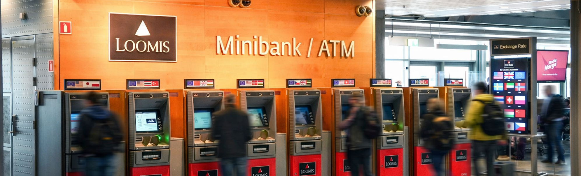 En person som bruker en minibank for utenlandsk valuta på en flyplass, med flere valutaalternativer vist på en skjerm i nærheten, som indikerer internasjonal reise og finansielle transaksjoner
