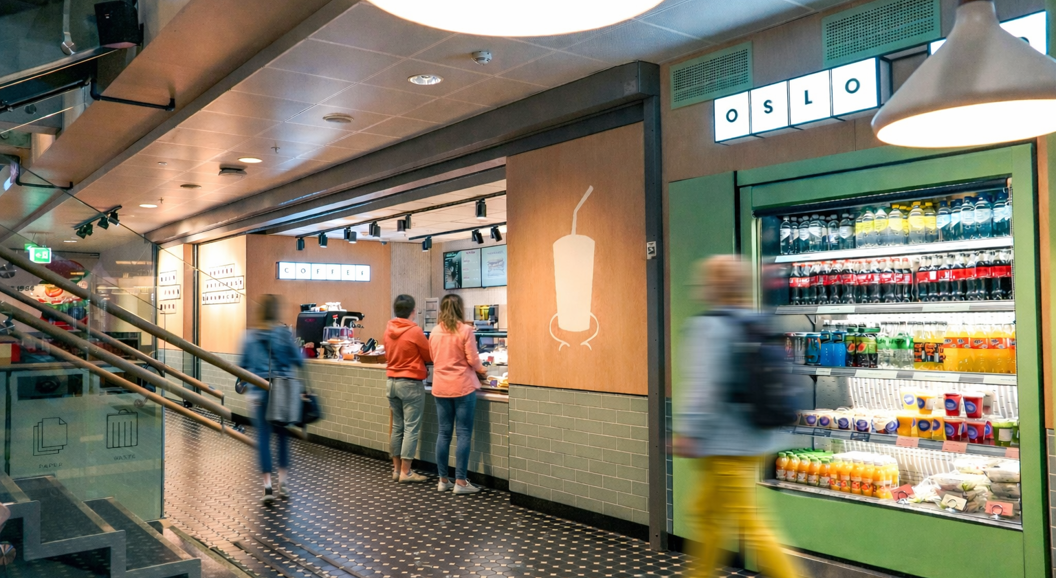 Moderne kaffebardisk med en ny meny vist på digitale skjermer, med en espressomaskin og et utvalg av kaffeforsyninger