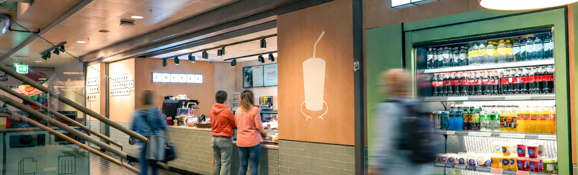 Moderne kaffebardisk med en ny meny vist på digitale skjermer, med en espressomaskin og et utvalg av kaffeforsyninger