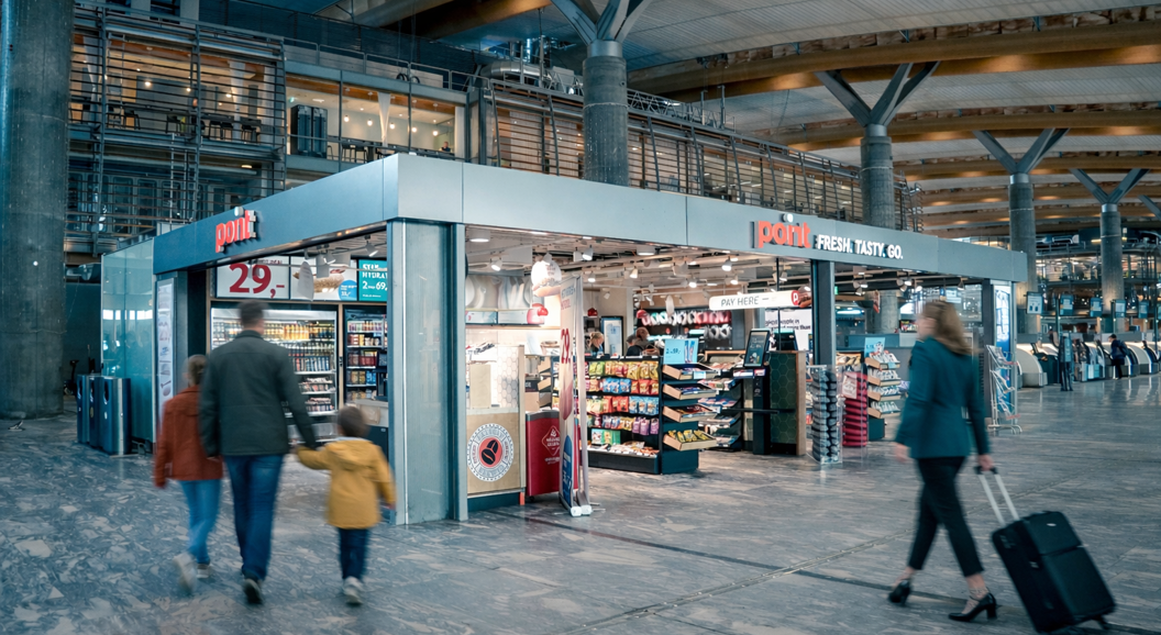 Convenience store kiosk in an airport terminal with snacks, drinks, and magazines displayed