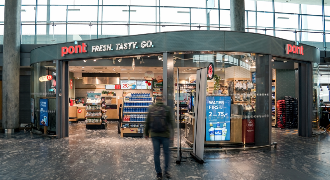 Skilt med teksten "Point Fresh Tasty Go" på ein kiosk i moderne design, inne i ein bygning