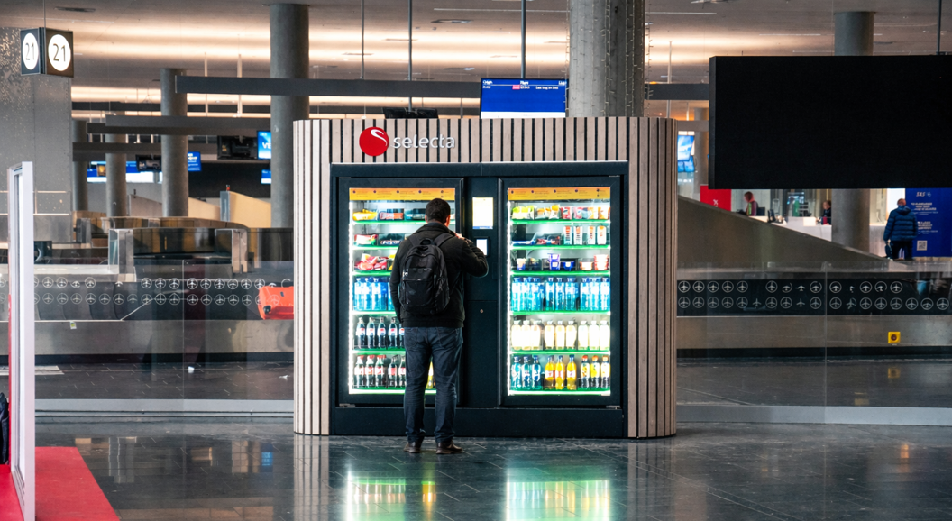 Automat fylt med diverse snacks og sjokoladebarer, inkludert kjente merker, med belyst valgpanel