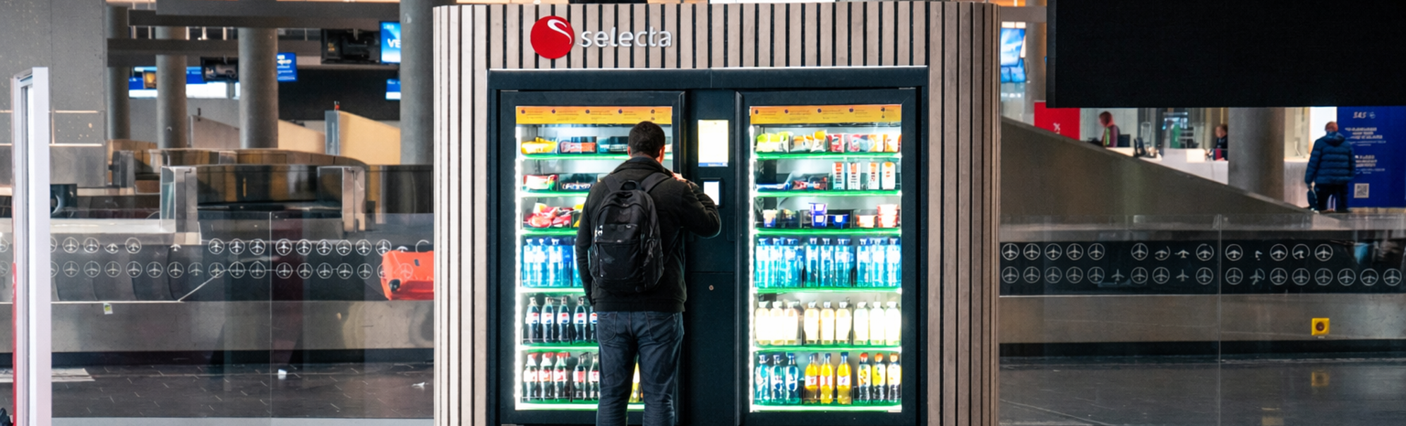 Automat fylt med diverse snacks og sjokoladebarer, inkludert kjente merker, med belyst valgpanel