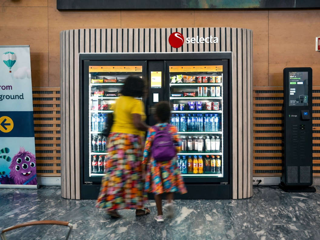 Automat fylt med assorterte snacks og sjokoladebarer, inkludert populære merker, med opplyst valgpanel
