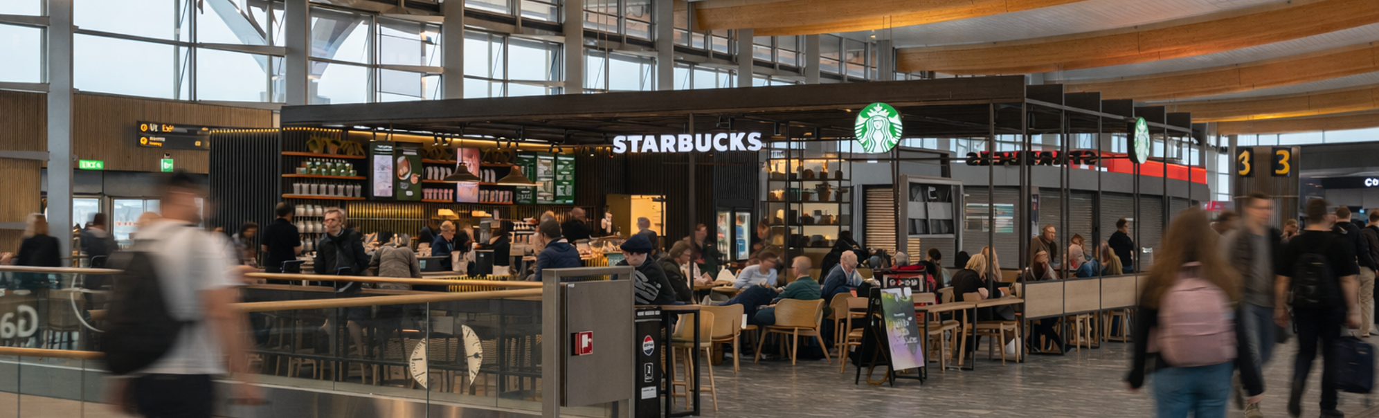 Person heller kaffe fra glass til kopp ved en kaffemaskin