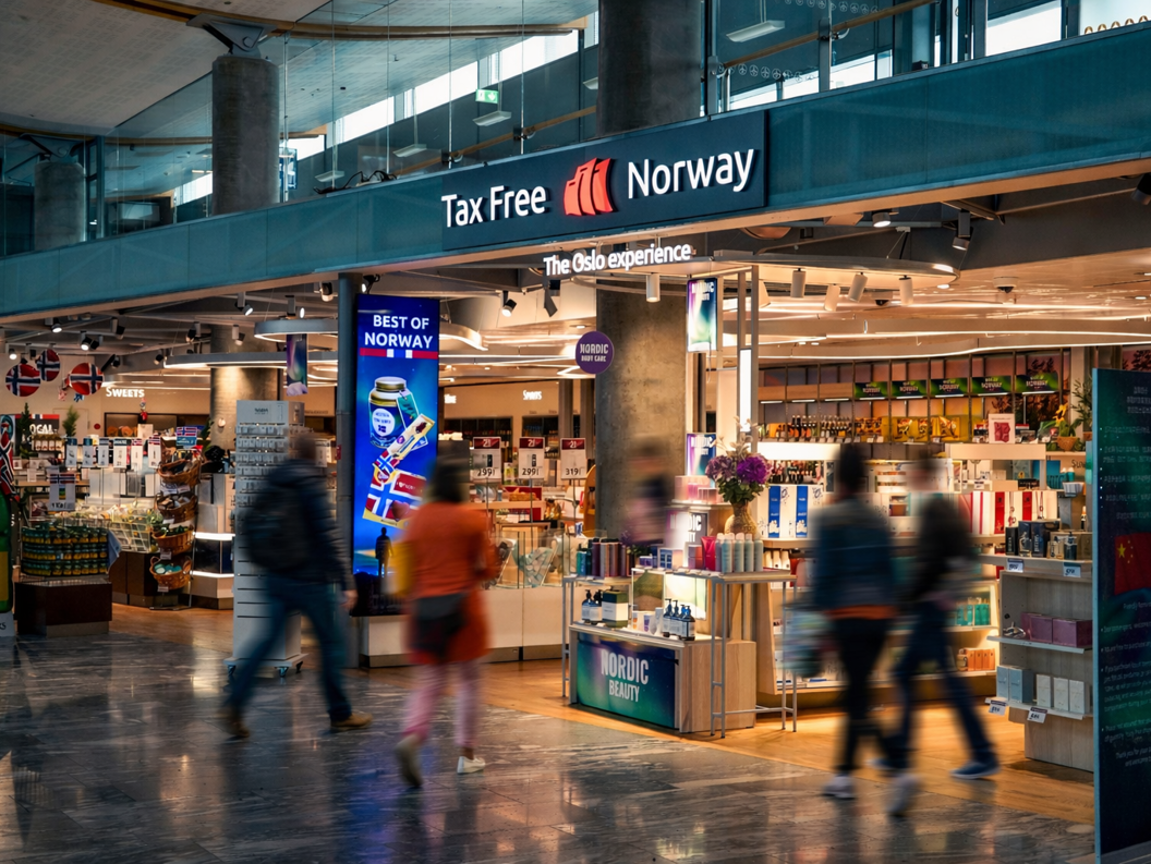 Woman shopping for sunglasses in a store, trying on a pair and smiling, wearing a black leather jacket
