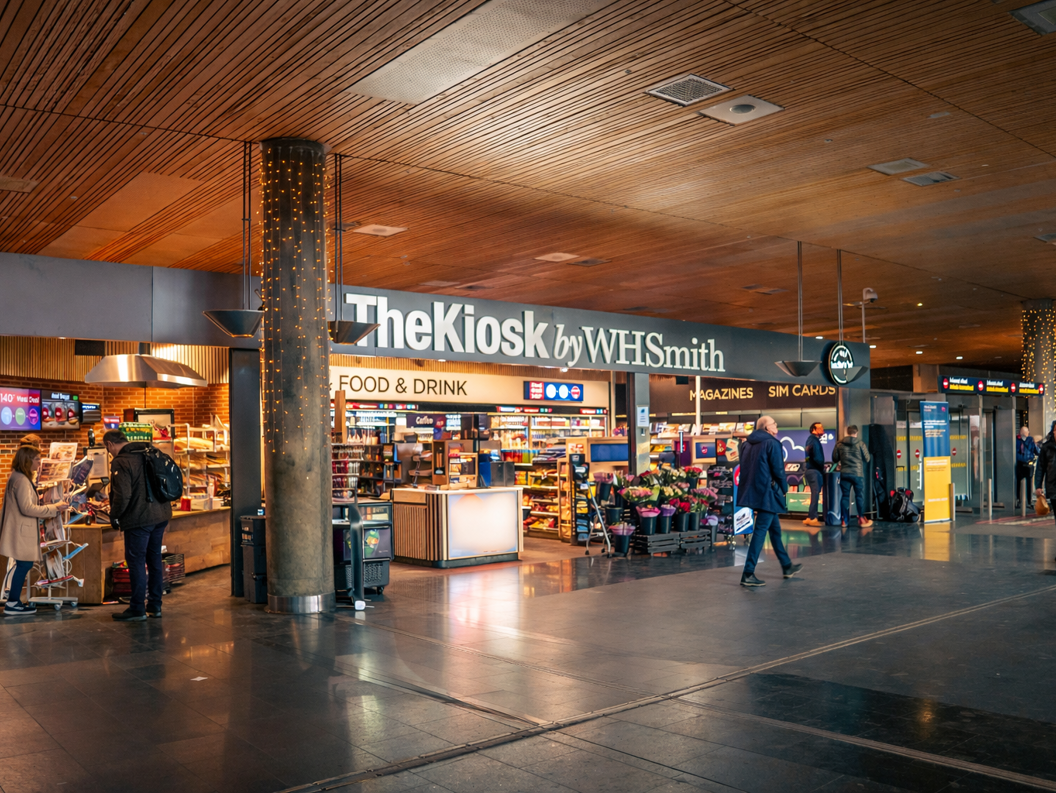 Moderne WHSmith-kiosk på en flyplass som tilbyr bekvemmelighetsvarer, snacks og drikkevarer under vibrerende belysning