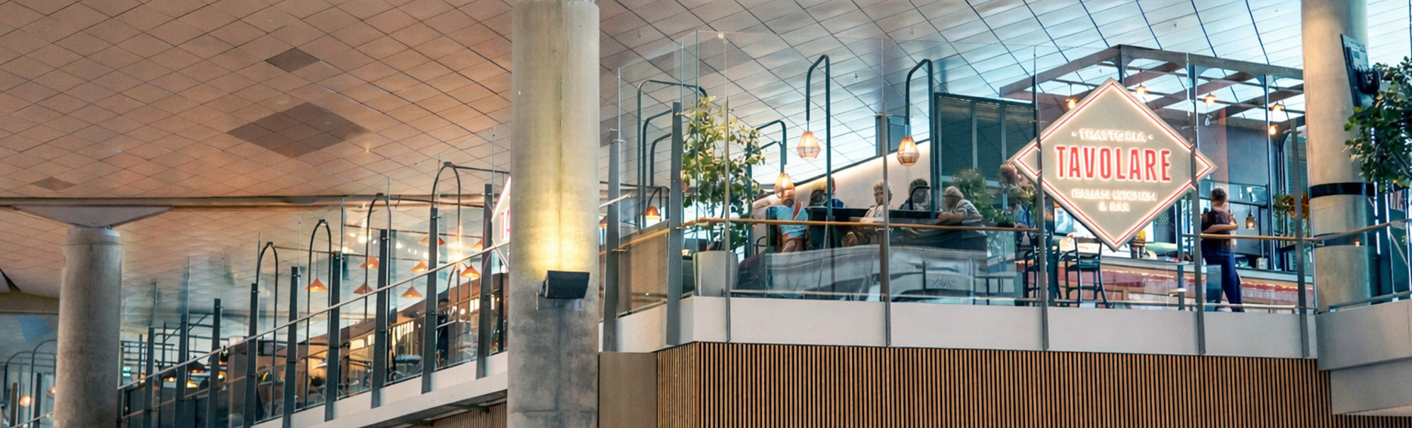 Tavolare Italian Kitchen & Bar-skilt innenfor et moderne kjøpesenter, med glassrekkverk og dekorativ belysning