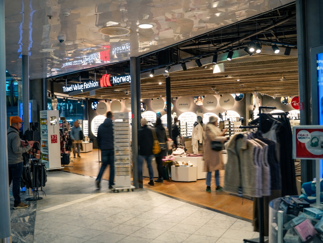 Kvinne ser på solbriller i ein butikk, omgitt av eit stort utval av briller på utstilling