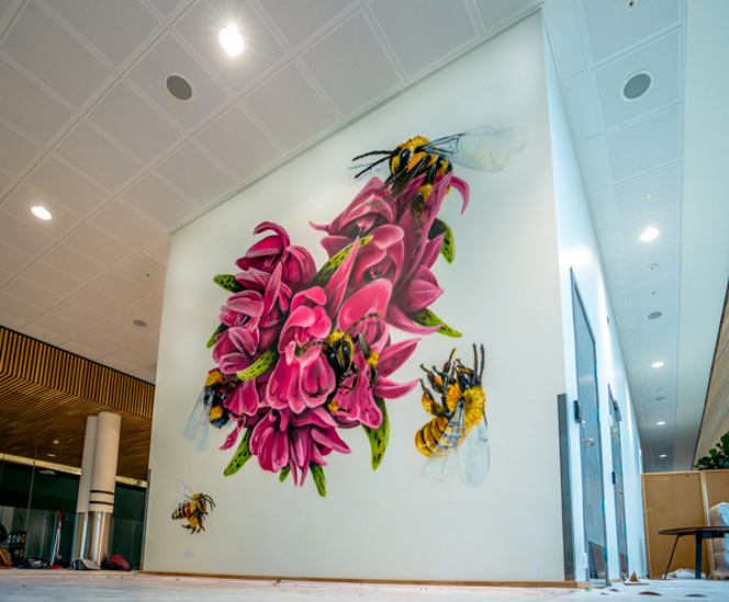 Kunstverk på Stavanger flyplass, en stor rosa orkide er malt på en vegg inne i terminalbygget